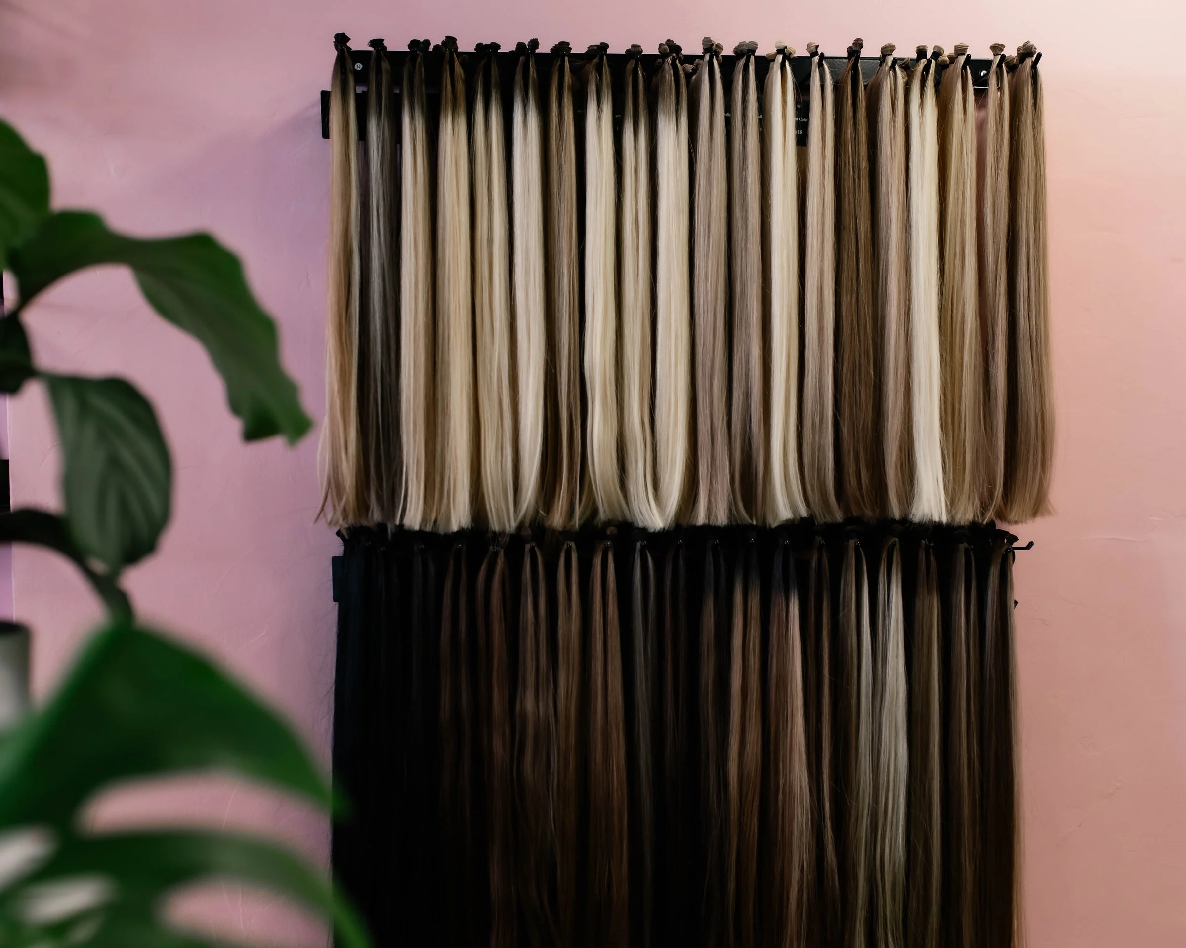Wefts in tientallen tinten blond en bruin aan de wand van de salon