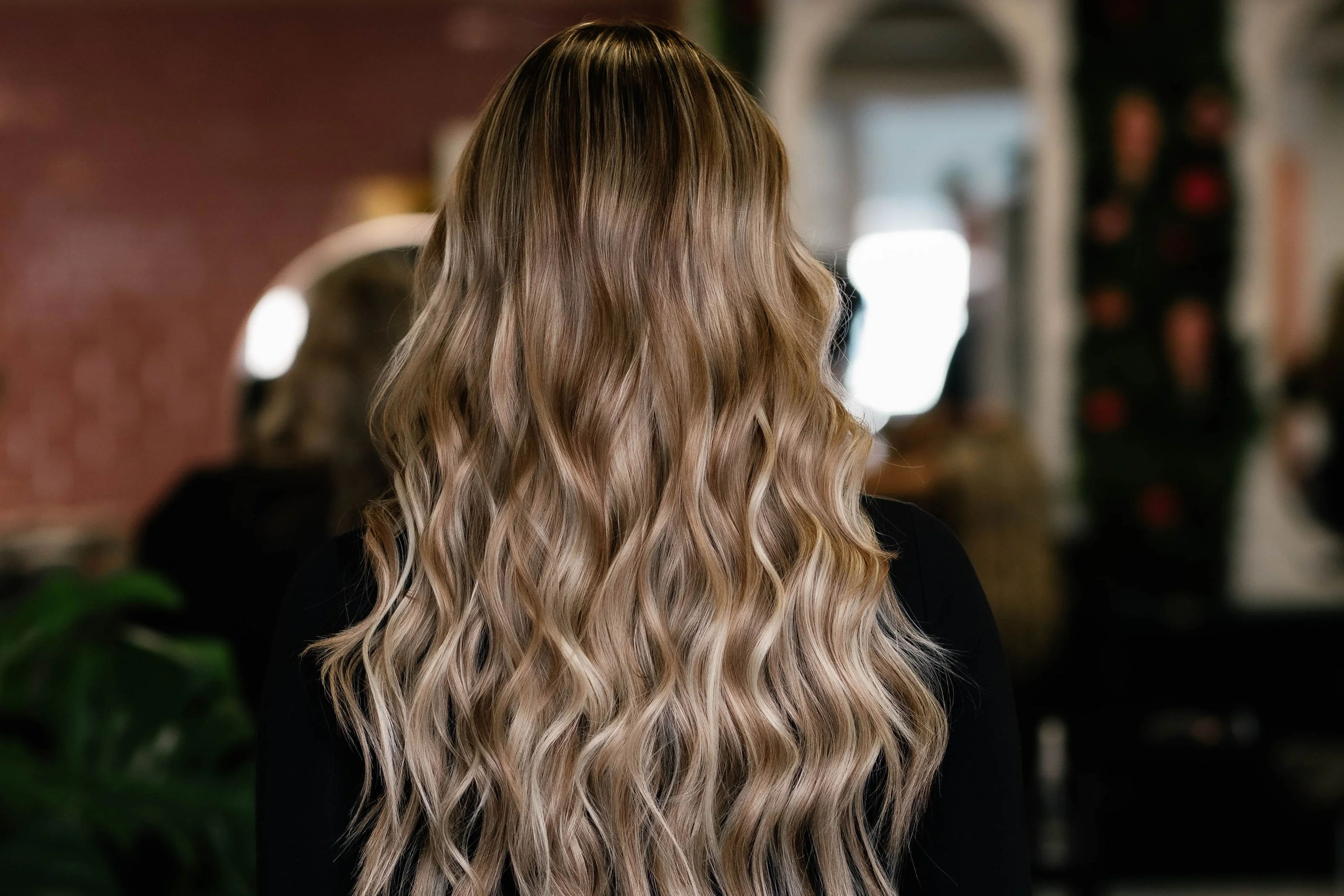 Lang golvend haar met balayage, van achteren gezien in de salon