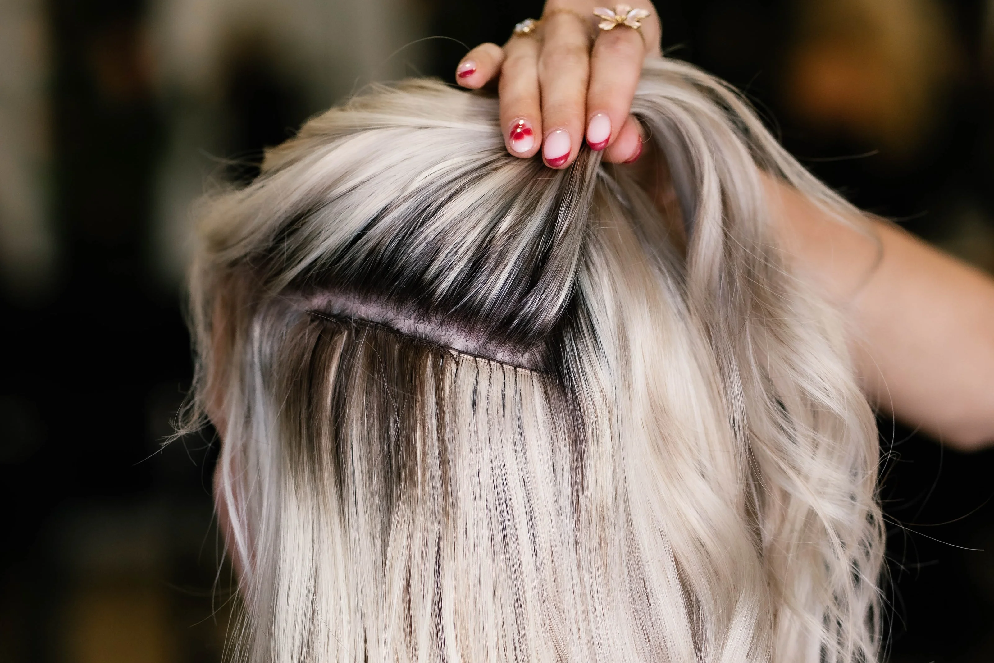 Close-up van ijsblond haar met donkere uitgroei en een rij extensions eronder