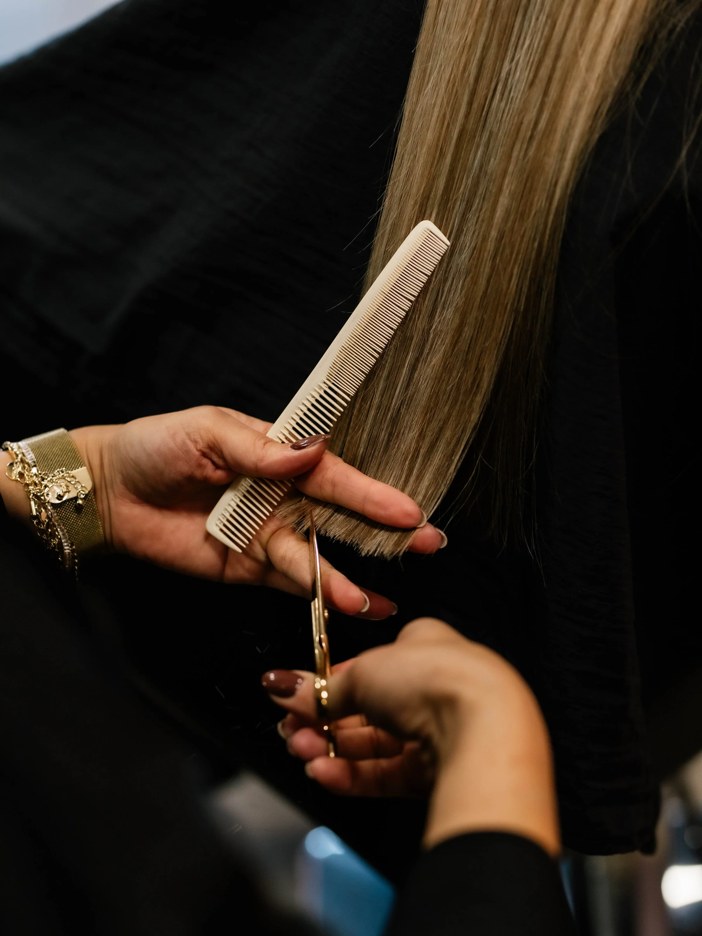 Close-up van kam en schaar bij het knippen van lang blond haar
