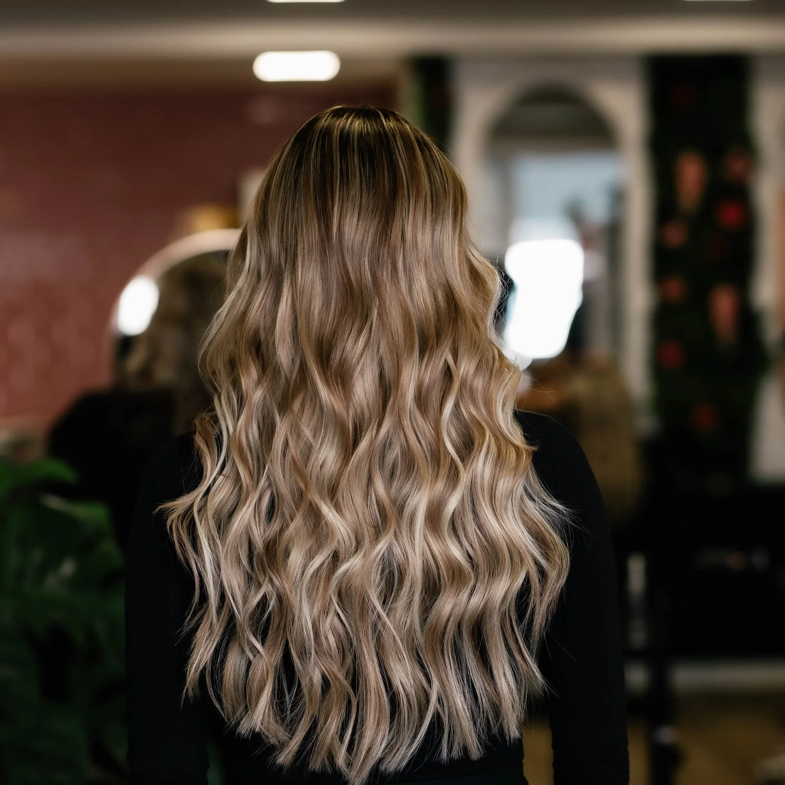 Dezelfde klant met lange losse krullen in warme blondtinten na het zetten van extensions