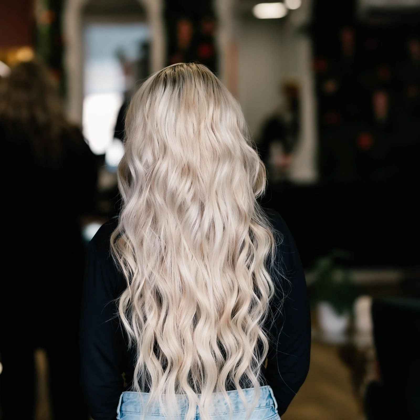 Dezelfde klant na de behandeling, met lang golvend blond haar, van achteren gezien