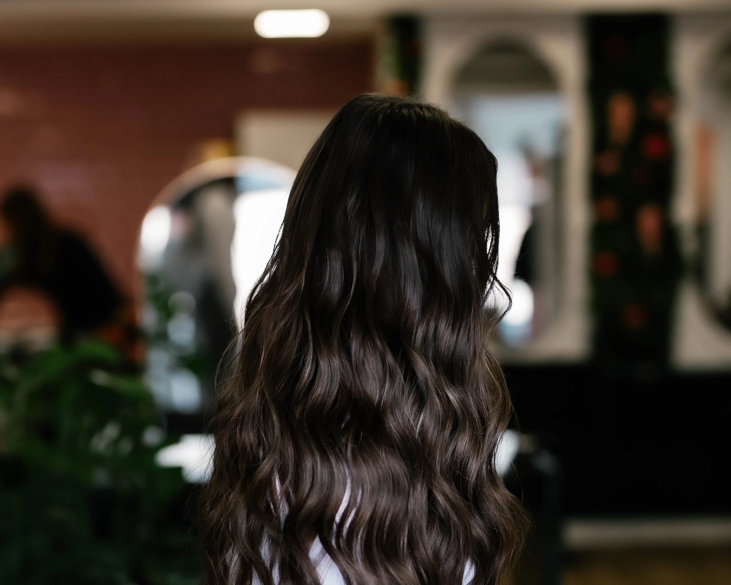 Lang donker haar met losse golven, van achteren gezien in de salon